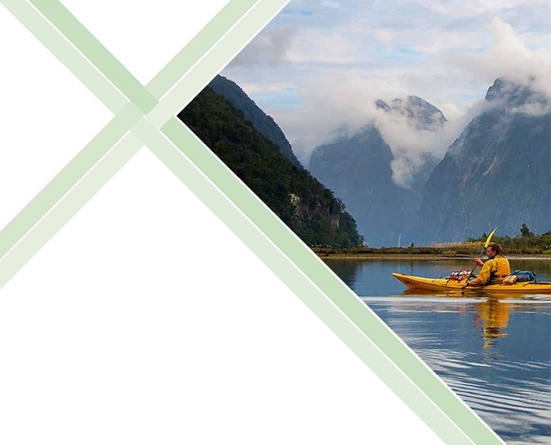 Man paddles a kayak on a still clear lake with a mountain backdrop