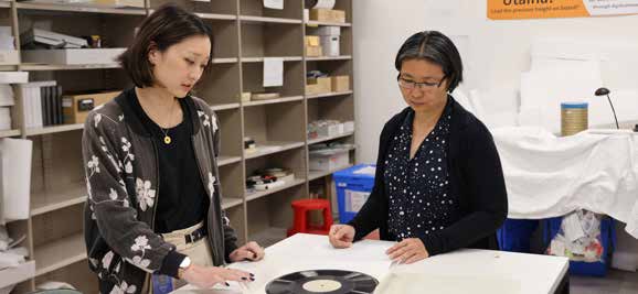 Archivists with vinyl record album, helping to digitise audio-visual media items.