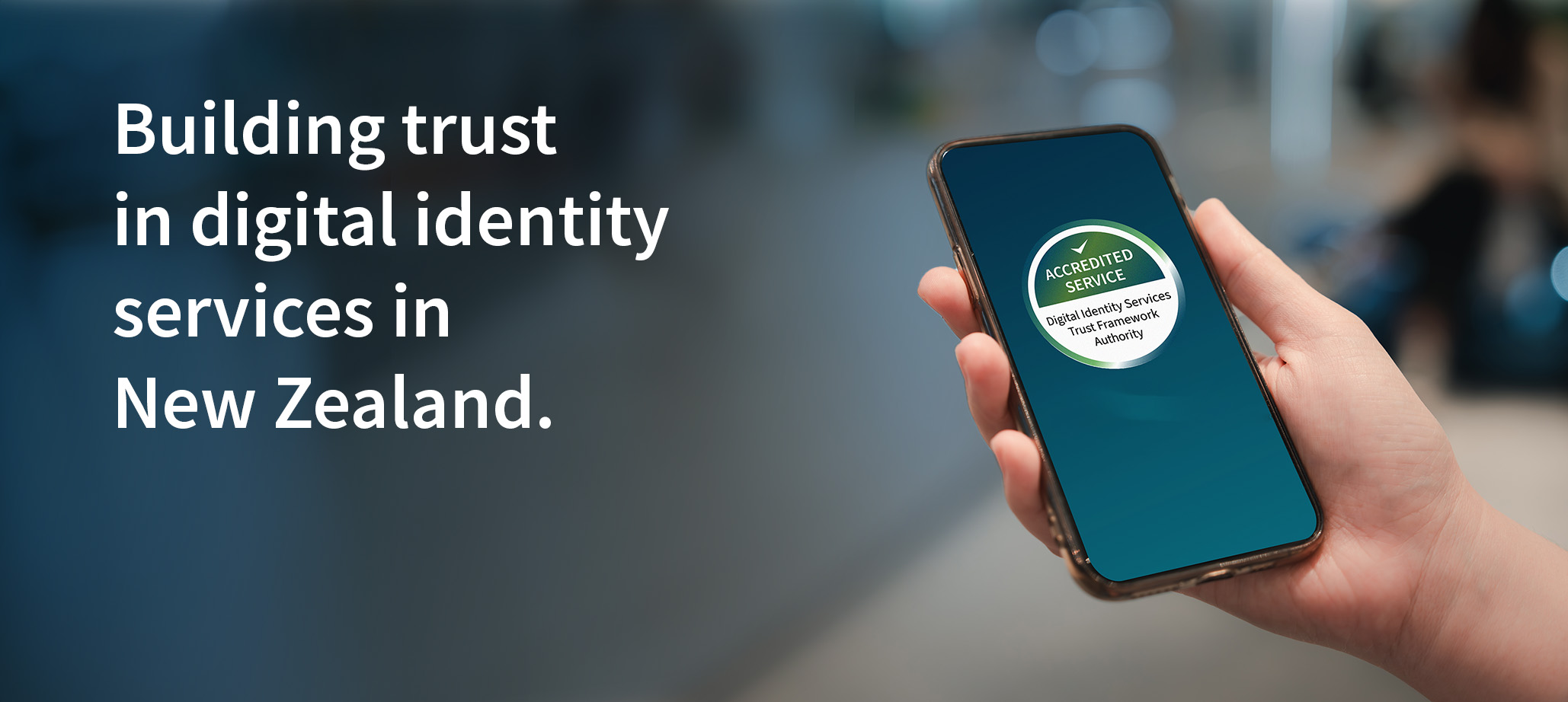 A hand holds a digital device labelled with the Mark of an Accredited Service from the Digital Identity Services Trust Framework Authority